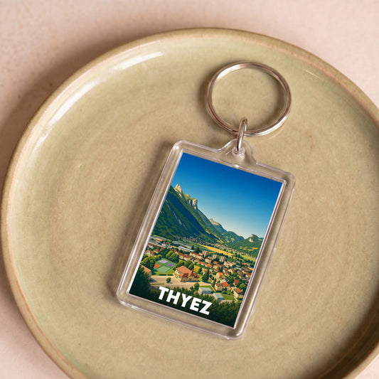 Porte-clés souvenir de la ville de Thyez avec une illustration stylisée de son paysage montagneux.