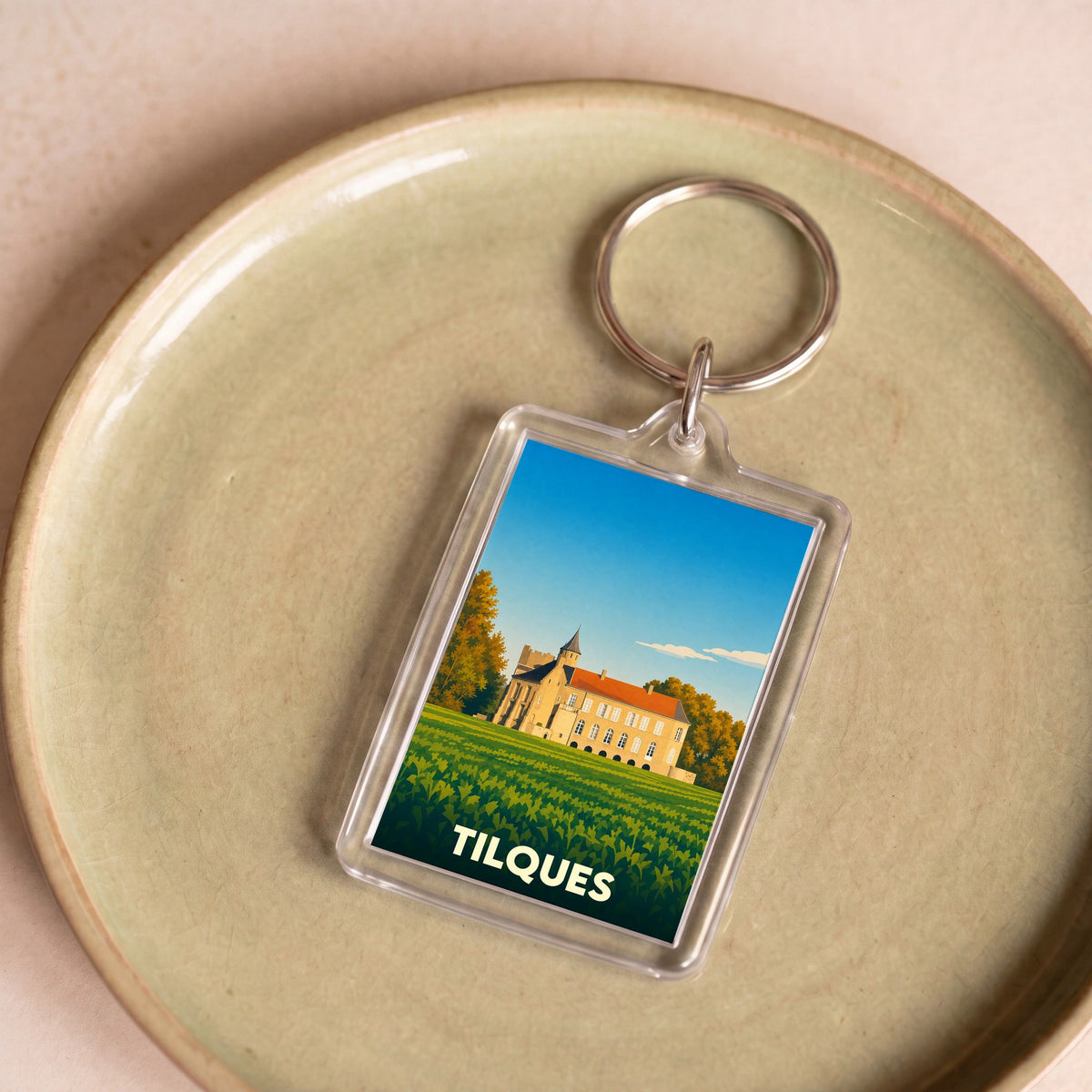 Porte-clés souvenir de la ville de Tilques avec une illustration stylisée de son château.