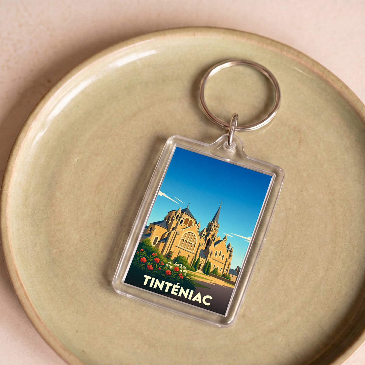Porte-clés souvenir de la ville de Tinténiac avec une illustration stylisée de son église.
