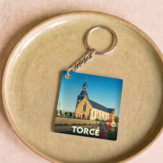 Porte-clés souvenir de la ville de Torcé avec une illustration stylisée de son église.
