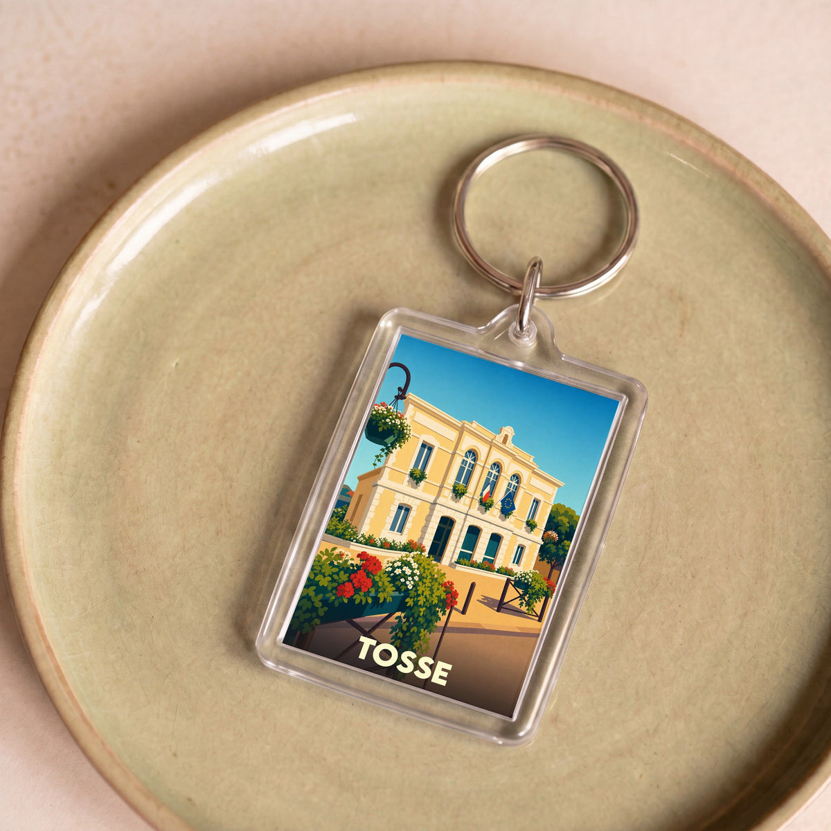Porte-clés souvenir de la ville de Tosse avec une illustration stylisée de sa mairie.
