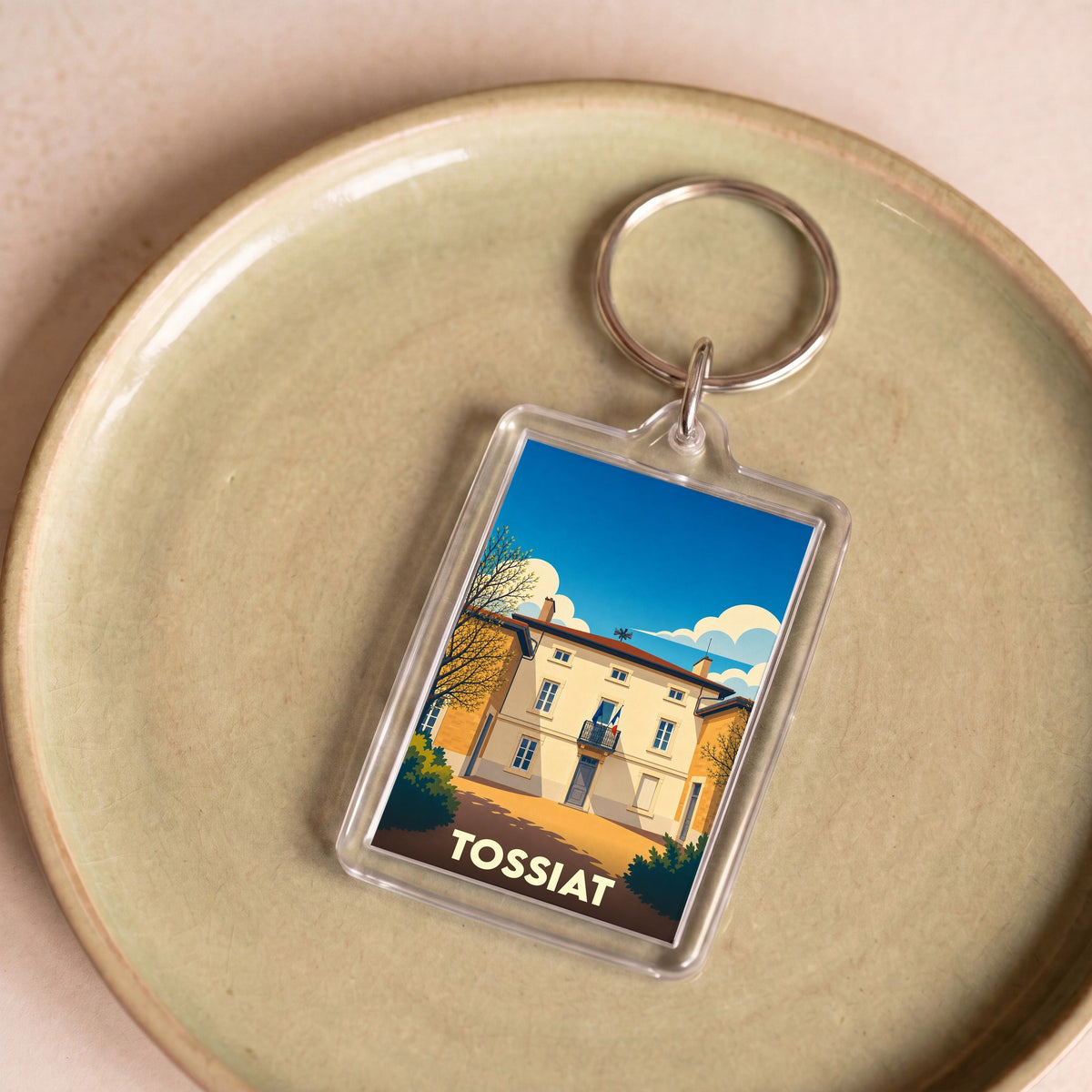 Porte-clés souvenir de la ville de Tossiat avec une illustration stylisée d'un bâtiment emblématique.