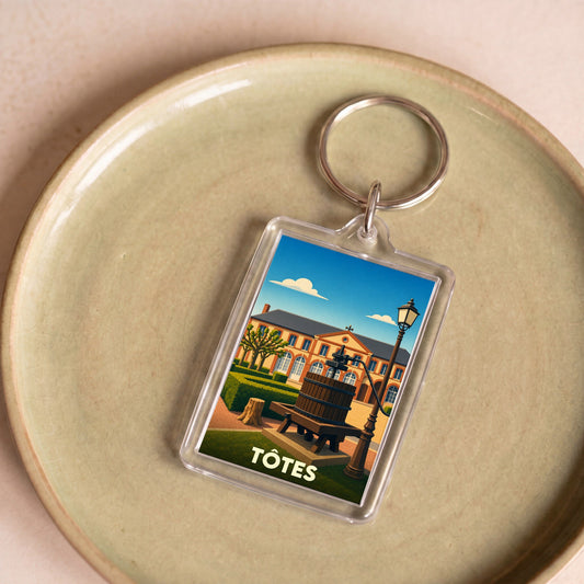 Porte-clés souvenir de la ville de Tôtes avec une illustration stylisée.