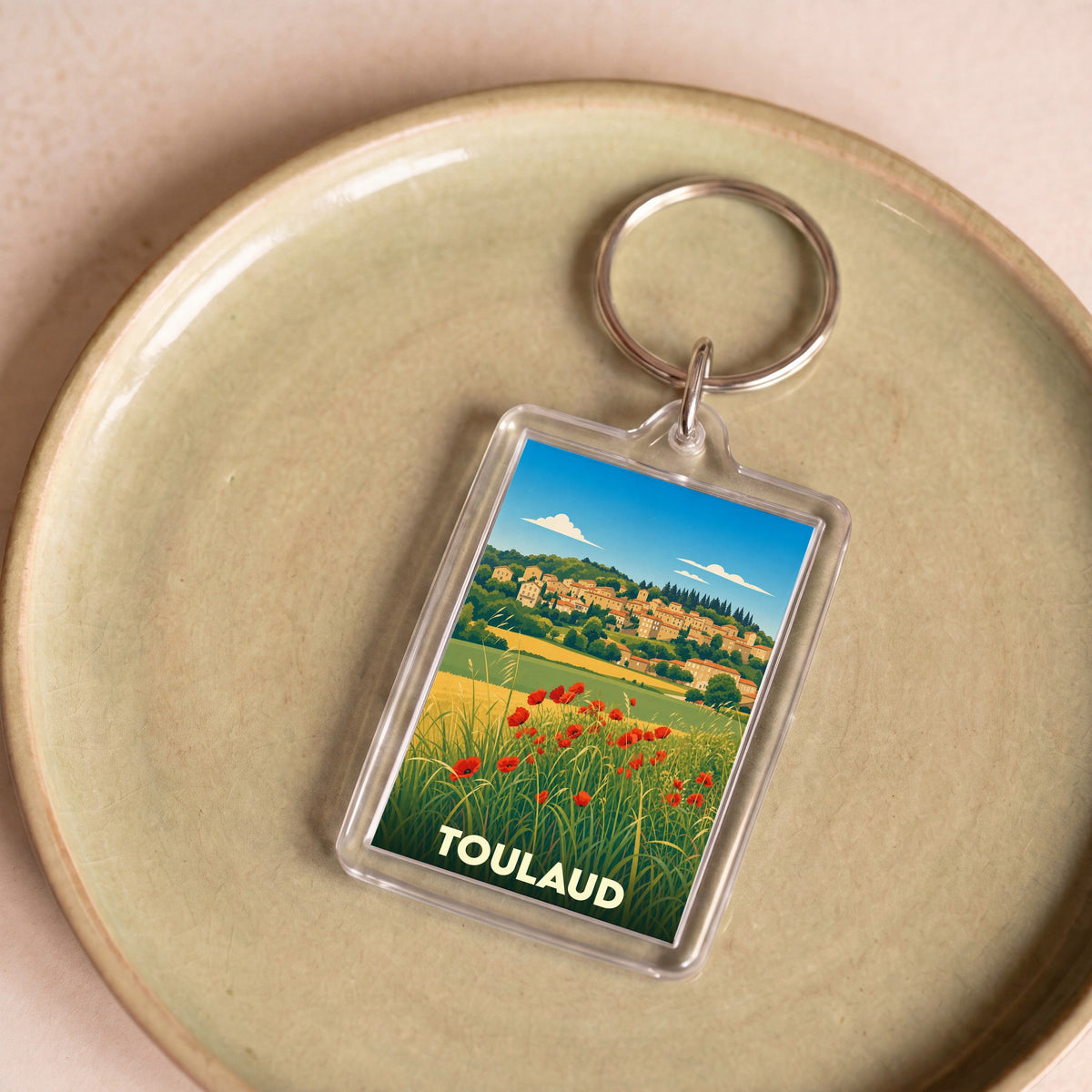 Porte-clés souvenir de la ville de Toulaud avec une illustration stylisée d'un paysage provençal.