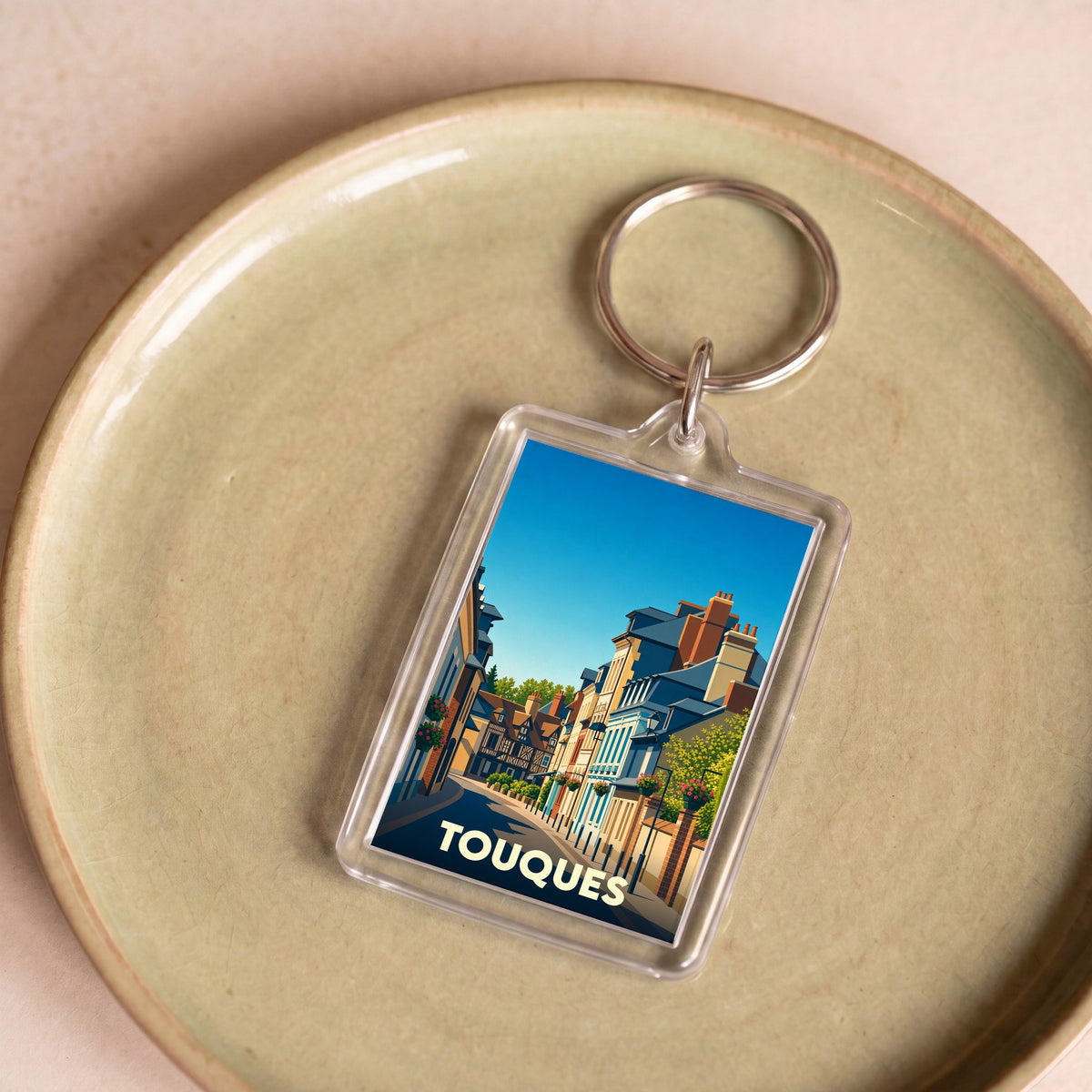 Porte-clés souvenir de la ville de Touques avec une illustration stylisée de ses rues pittoresques.