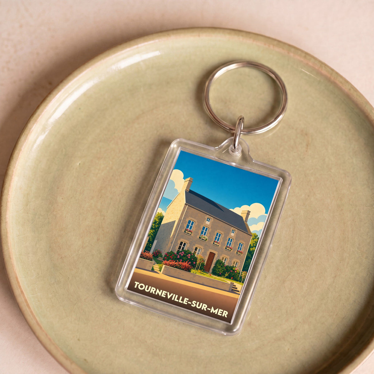 Porte-clés souvenir de la ville de Tourneville-sur-Mer avec une illustration stylisée d'une maison côtière.