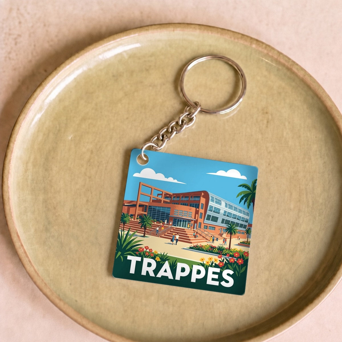 Porte-clés souvenir de la ville de Trappes avec une illustration stylisée et colorée.