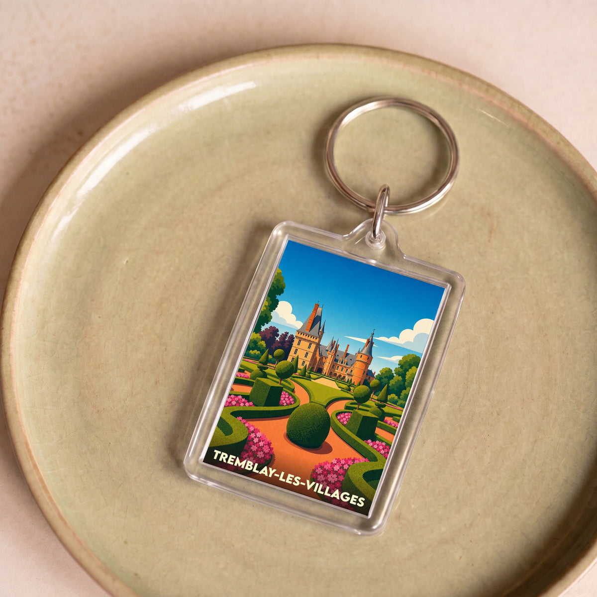 Porte-clés souvenir de la ville de Tremblay-les-Villages avec une illustration stylisée d'un château et de ses jardins.