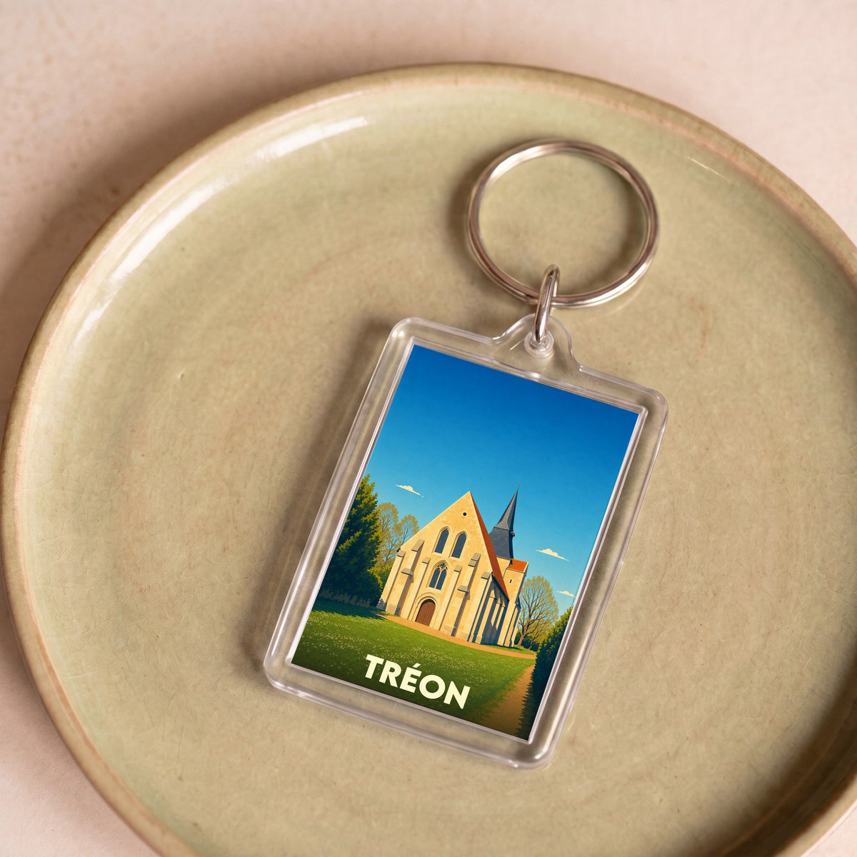 Porte-clés souvenir de la ville de Tréon avec une illustration stylisée de son église.