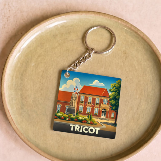 Porte-clés souvenir de la ville de Tricot avec une illustration stylisée.