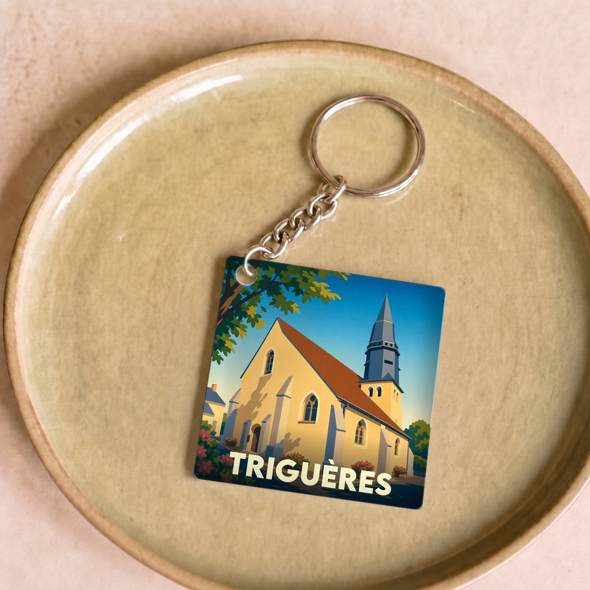 Porte-clés souvenir de la ville de Triguères avec une illustration stylisée de son église.