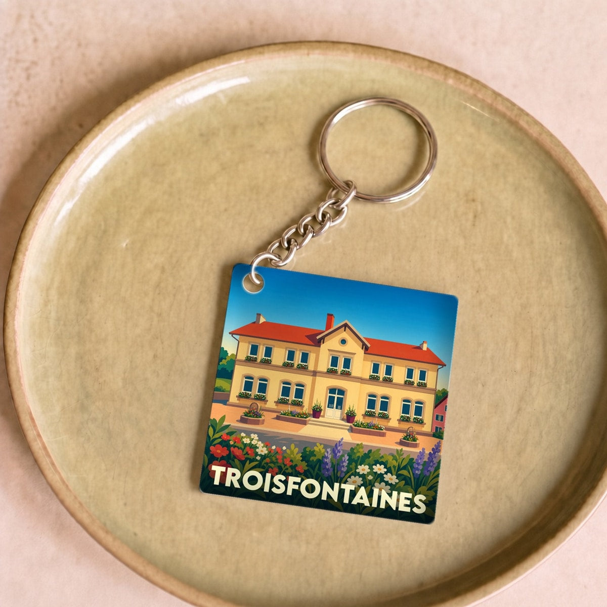 Porte-clés souvenir de la ville de Troisfontaines avec une illustration colorée et stylisée.