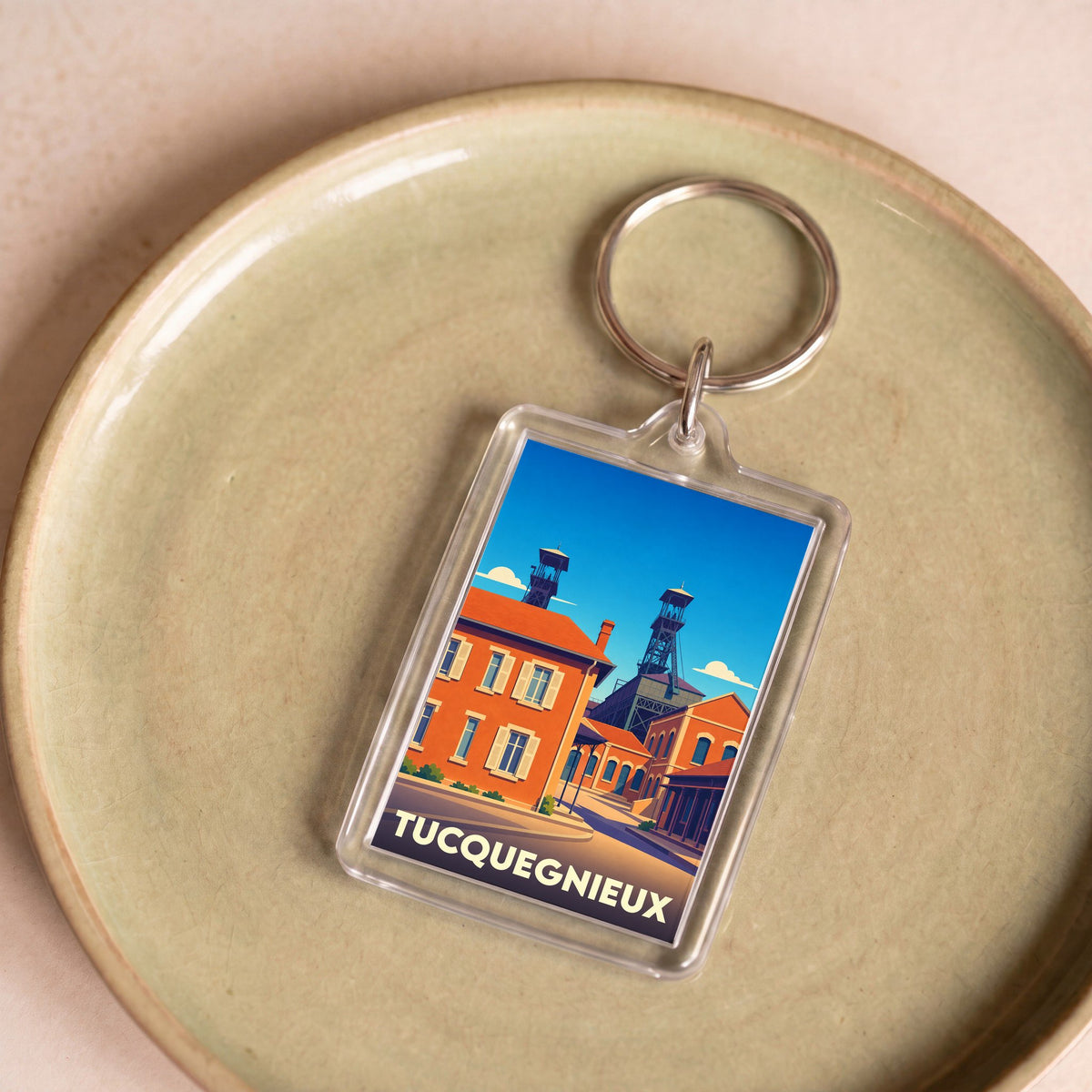 Porte-clés souvenir de la ville de Tucquegnieux avec une illustration stylisée montrant des chevalements de mine.