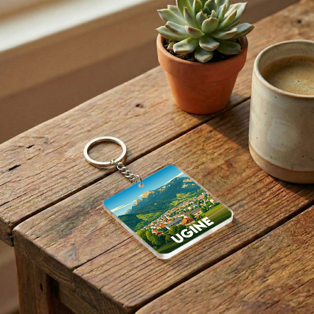 Porte-clés souvenir de la ville d'Ugine avec une illustration stylisée d'un paysage montagneux.