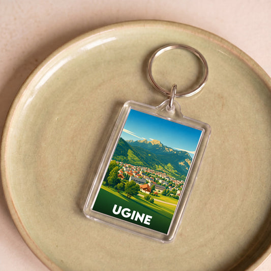 Porte-clés souvenir de la ville d'Ugine avec une illustration stylisée d'un paysage montagneux.