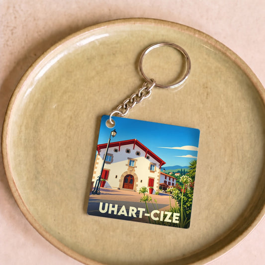 Porte-clés souvenir de la ville d'Uhart-Cize avec une illustration stylisée d'une maison basque traditionnelle.