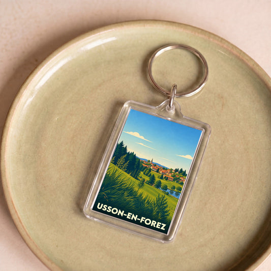 Porte-clés souvenir de la ville de Usson-en-Forez avec une illustration stylisée de son paysage.