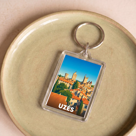 Porte-clés souvenir de la ville d'Uzès avec une illustration stylisée de ses toits et clochers.