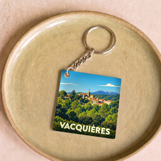 Porte-clés souvenir de la ville de Vacquières avec une illustration stylisée d'un village provençal.