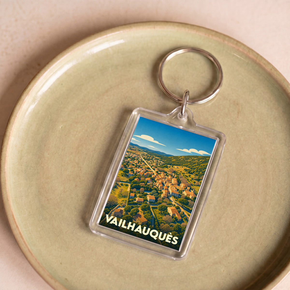 Porte-clés souvenir de la ville de Vailhauquès avec une illustration stylisée.