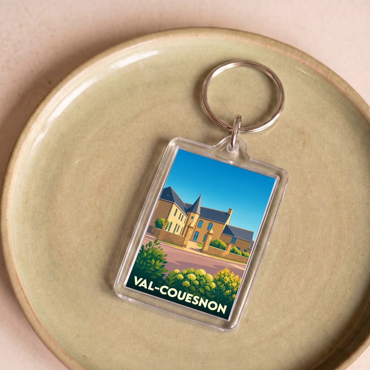 Porte-clés souvenir de la ville de Val-Couesnon avec une illustration stylisée d'un bâtiment historique.