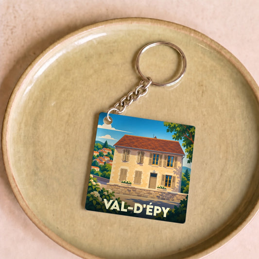 Porte-clés souvenir de Val-d'Épy avec une illustration stylisée d'une maison traditionnelle.