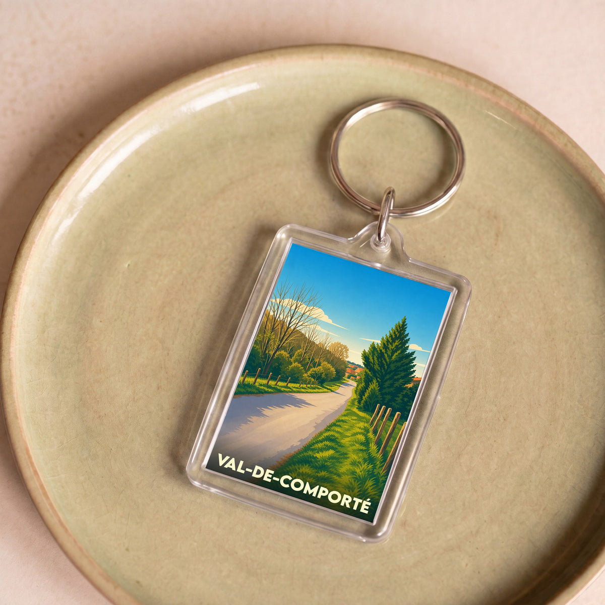 Porte-clés souvenir de Val-de-Comporté avec une illustration stylisée d'un paysage rural.