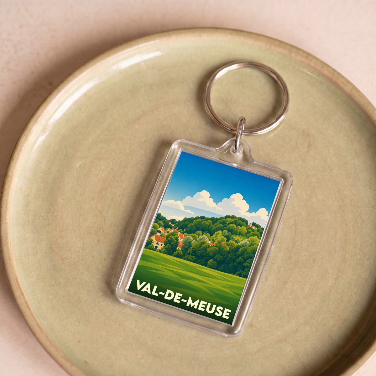 Porte-clés souvenir de Val-de-Meuse avec une illustration stylisée de paysages verdoyants.