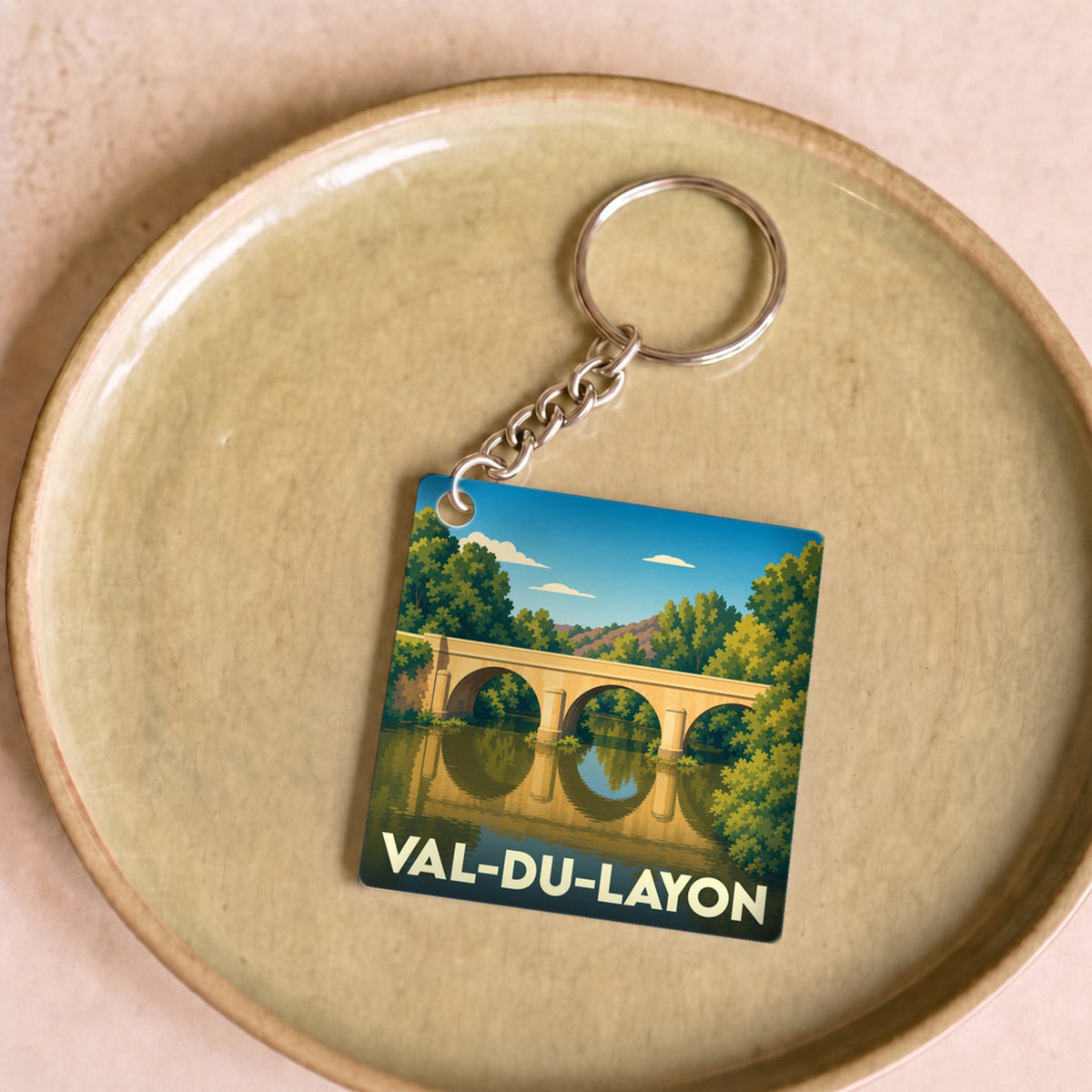 Porte-clés souvenir de Val-du-Layon avec une illustration stylisée d'un pont se reflétant dans l'eau.