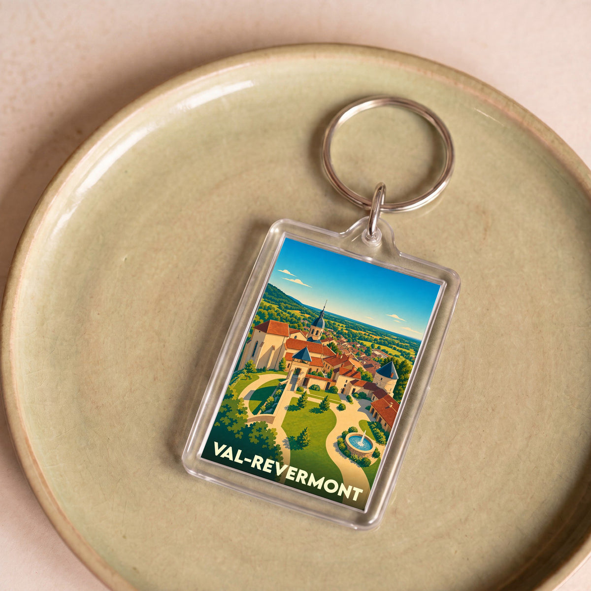 Porte-clés souvenir de la ville de Val-Revermont avec une illustration stylisée de son paysage urbain.