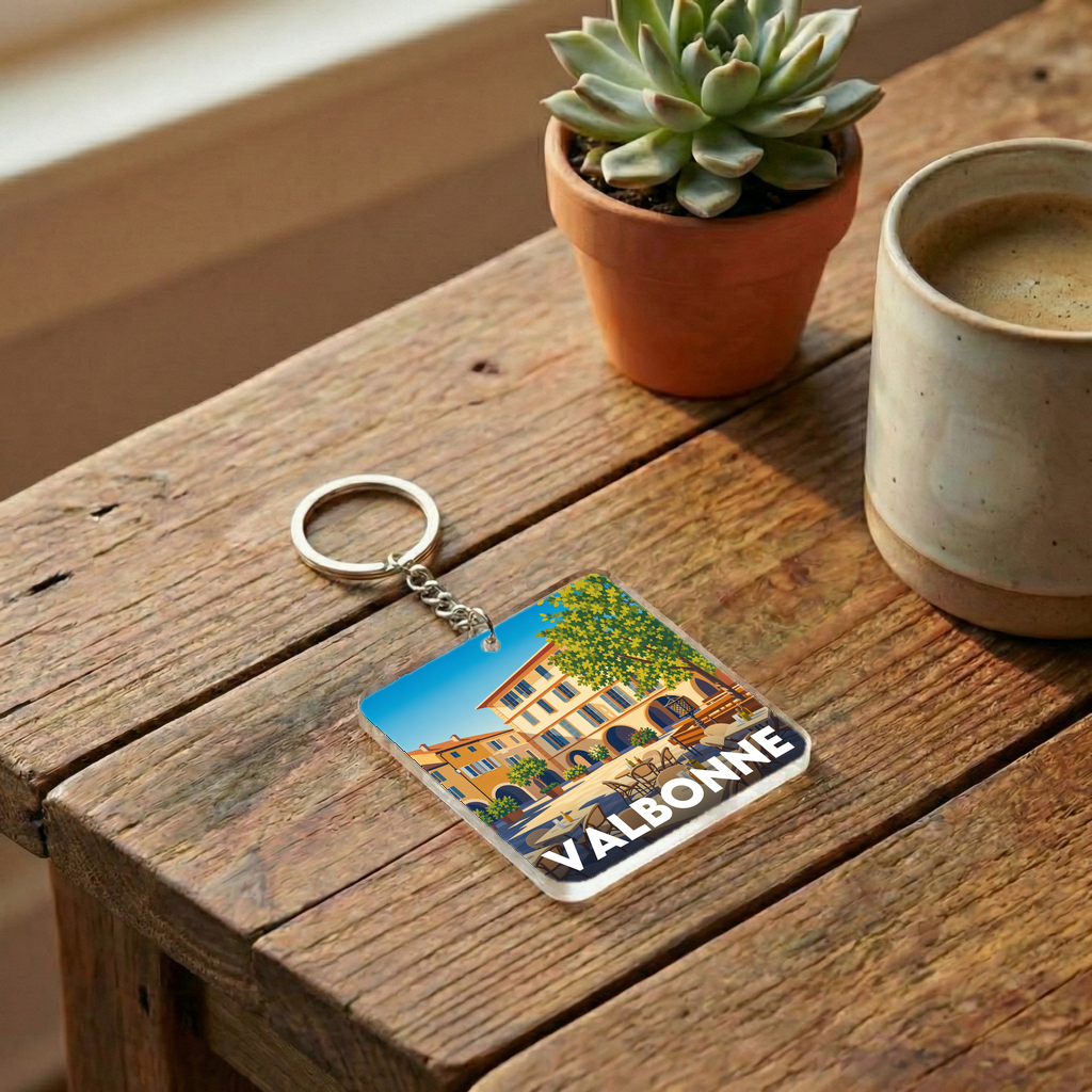 Porte-clés souvenir de la ville de Valbonne avec une illustration stylisée d'une place ensoleillée.