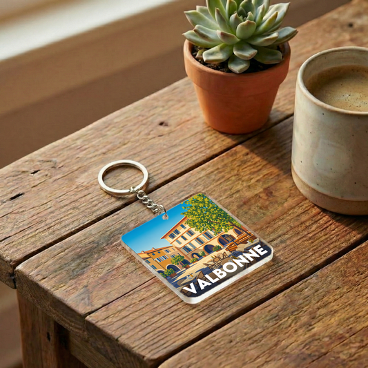 Porte-clés souvenir de la ville de Valbonne avec une illustration stylisée d'une place ensoleillée.