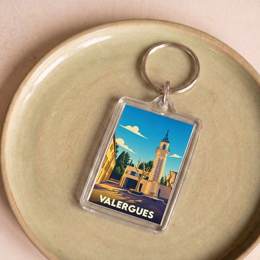 Porte-clés souvenir de la ville de Valergues avec une illustration stylisée de son église et de son horloge.