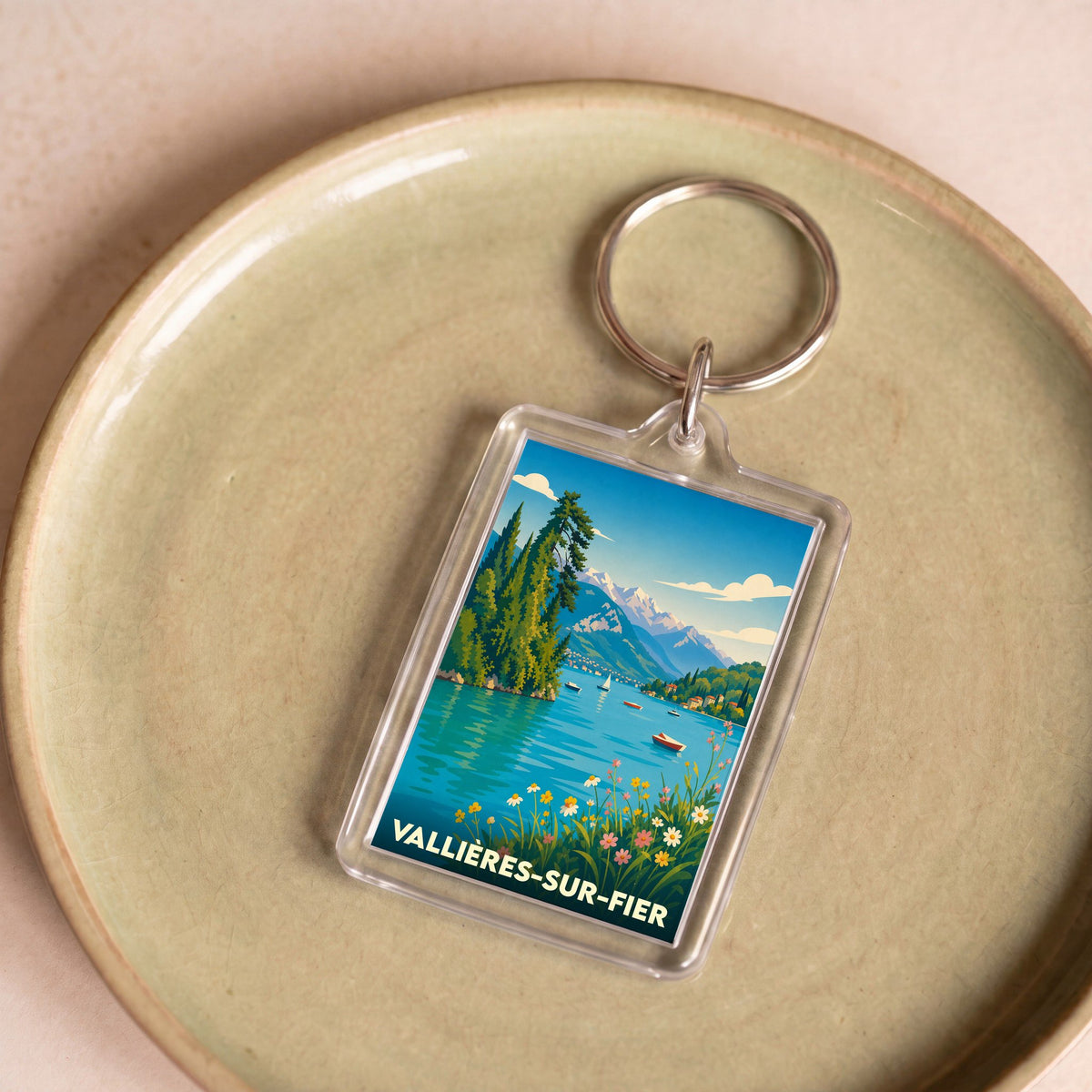 Porte-clés souvenir de la ville de Vallières-sur-Fier avec une illustration stylisée de lac et de montagnes.