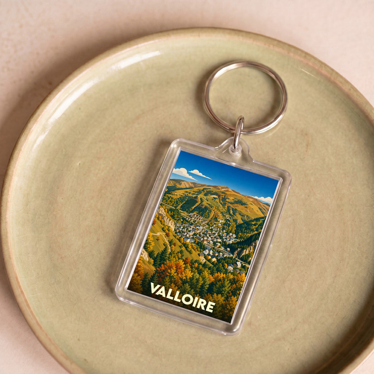 Porte-clés souvenir de la ville de Valloire avec une illustration stylisée de montagne en automne.