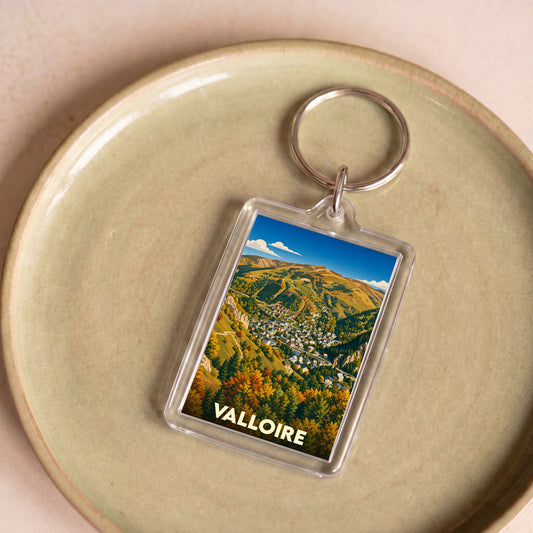 Porte-clés souvenir de la ville de Valloire avec une illustration stylisée de montagne en automne.