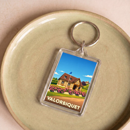 Porte-clés souvenir de la commune de Valorbiquet avec une illustration stylisée d'une maison normande fleurie.