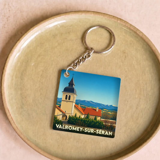 Porte-clés souvenir de Valromey-sur-Séran avec une illustration stylisée de son église et des montagnes.