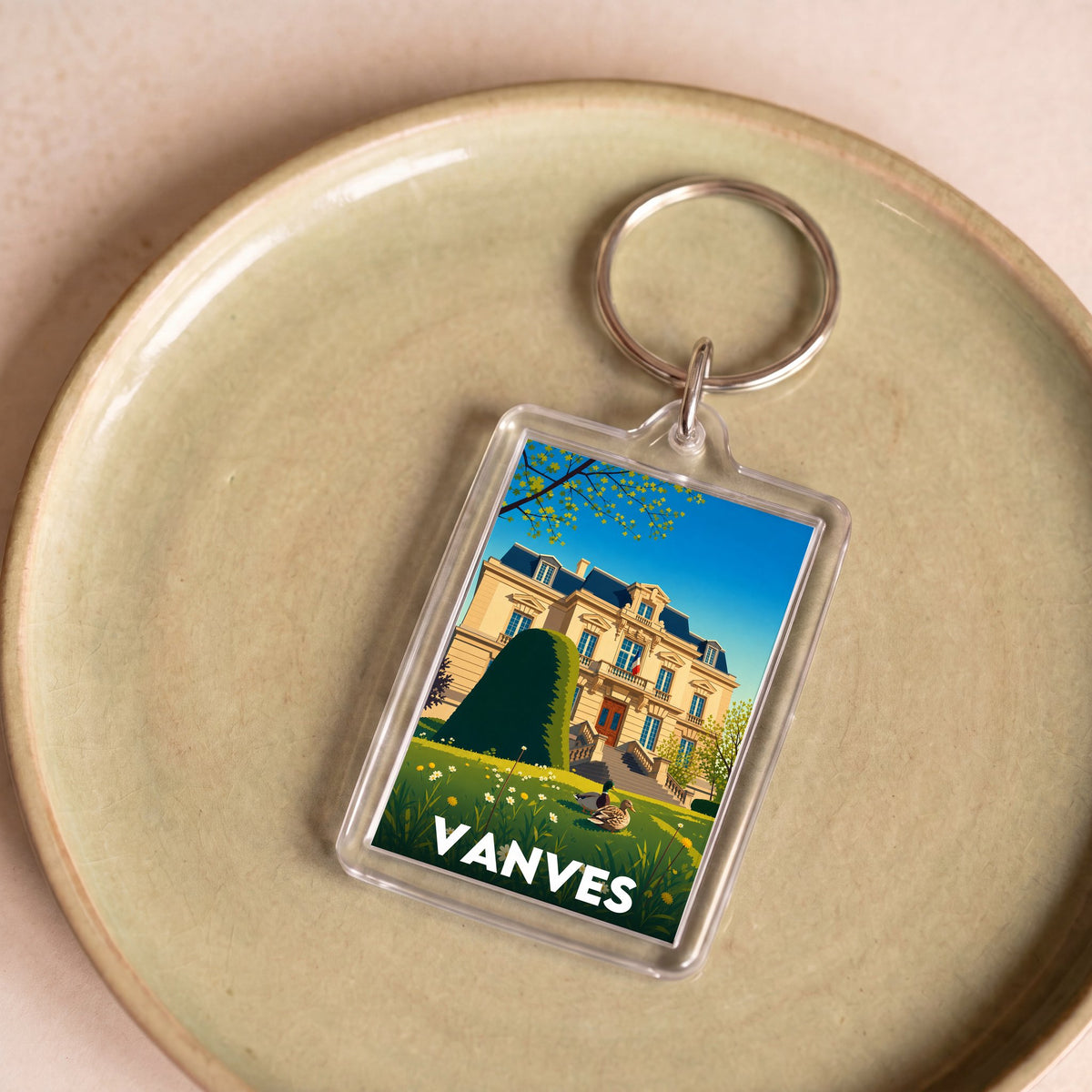 Porte-clés souvenir de la ville de Vanves avec une illustration stylisée d'un bâtiment historique.