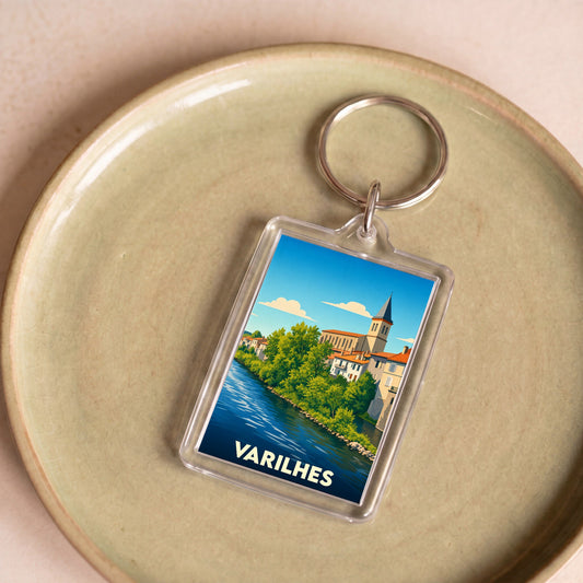Porte-clés souvenir de la ville de Varilhes avec une illustration stylisée d'un paysage urbain au bord de l'eau.