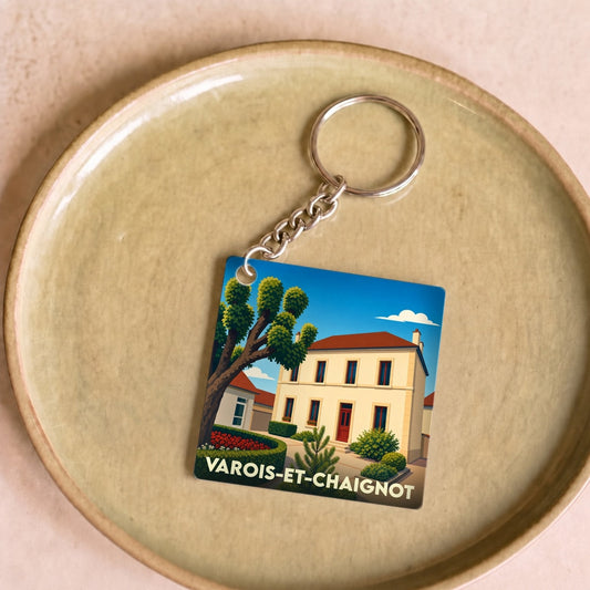 Porte-clés souvenir de la ville de Varois-et-Chaignot avec une illustration stylisée d'une maison de village.