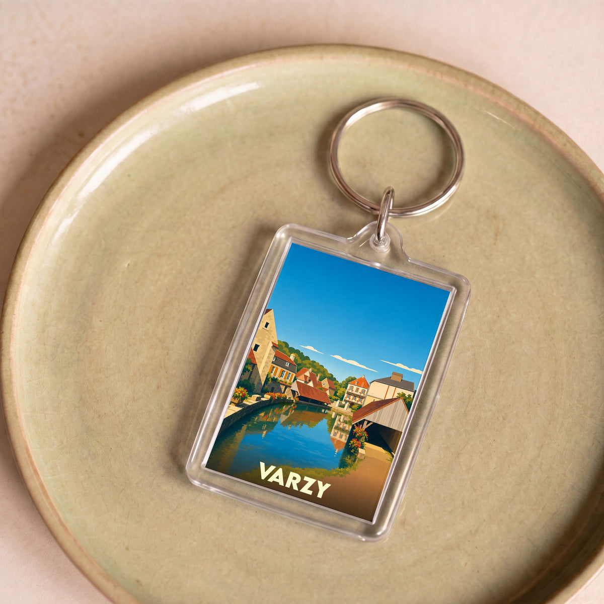 Porte-clés souvenir de la ville de Varzy avec une illustration stylisée d'un canal bordé de maisons.