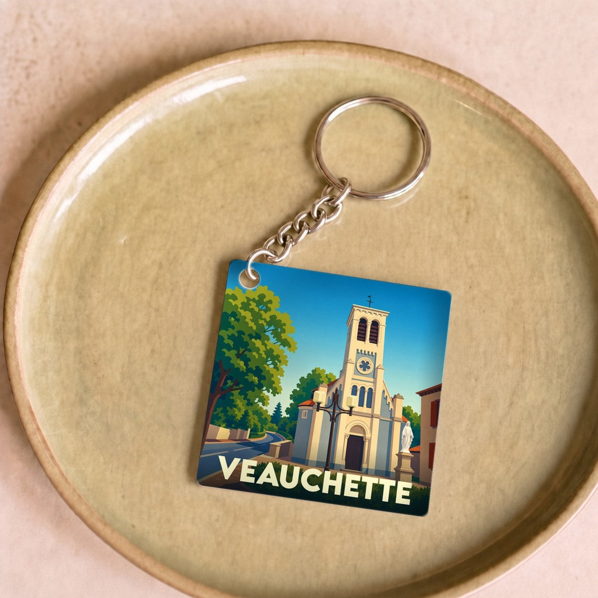 Porte-clés souvenir de la ville de Veauchette avec une illustration stylisée de son église.