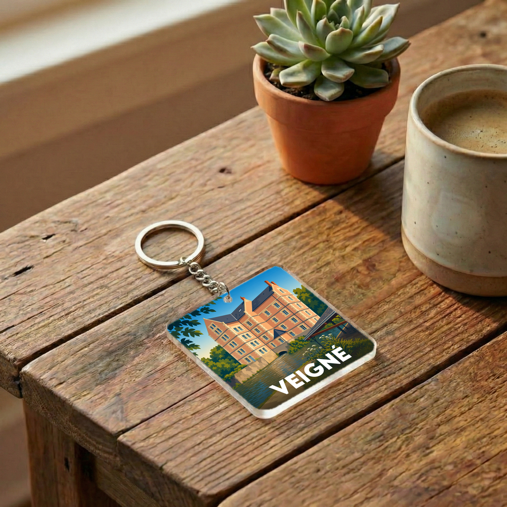 Porte-clés souvenir de la ville de Veigné avec une illustration stylisée d'un château au bord de l'eau.
