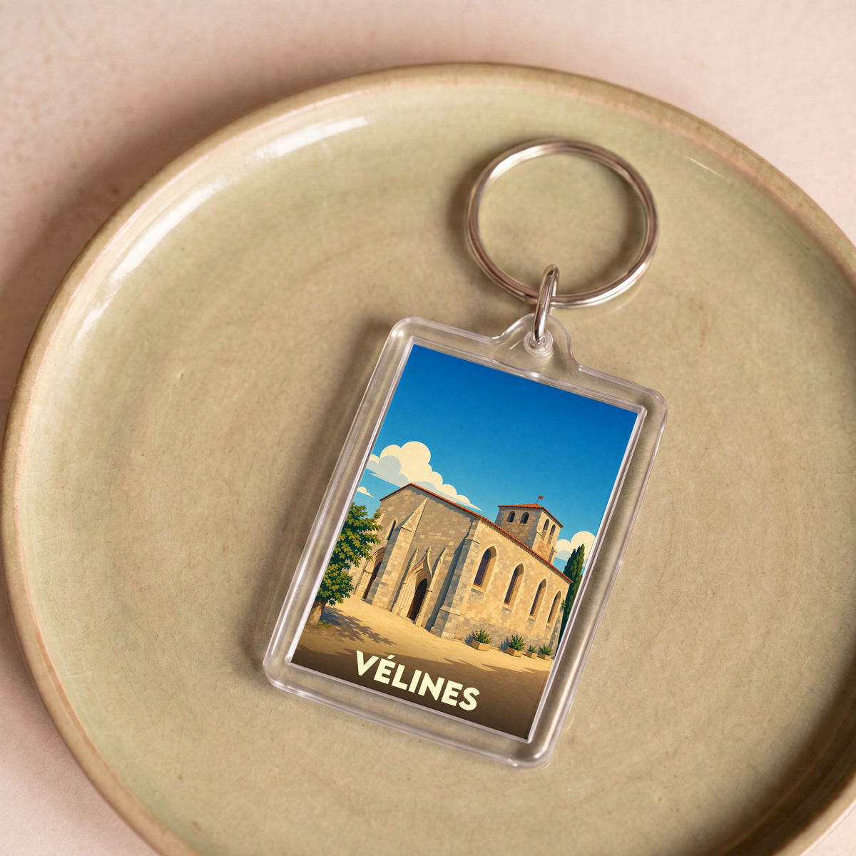 Porte-clés souvenir de la ville de Vélines avec une illustration stylisée de son église.