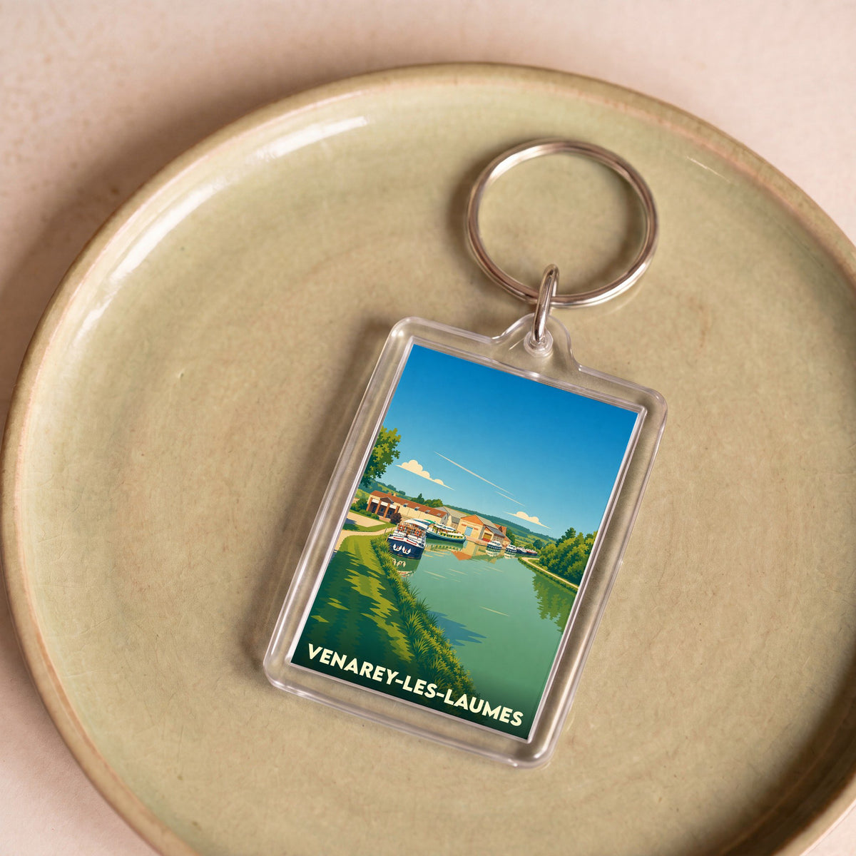 Porte-clés souvenir de la ville de Venarey-les-Laumes avec une illustration stylisée d'un canal et de bateaux.