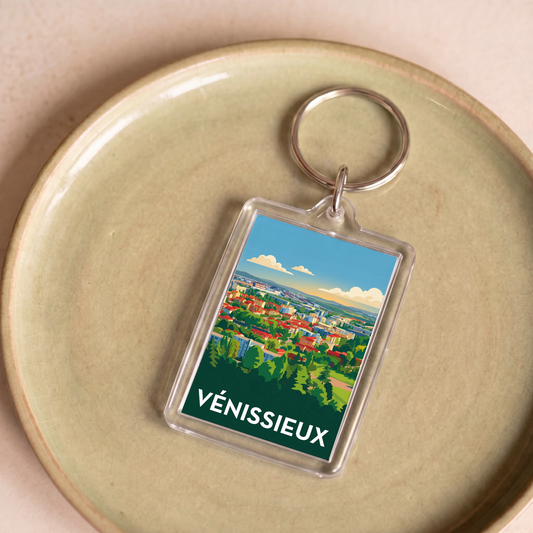 Porte-clés souvenir de la ville de Vénissieux avec une illustration stylisée du paysage urbain.