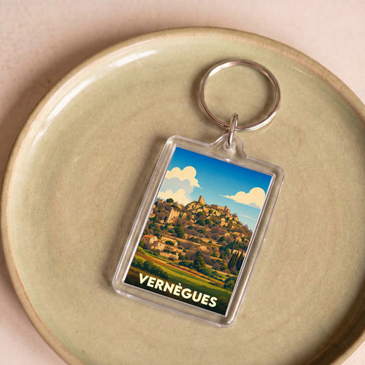 Porte-clés souvenir de la ville de Vernègues avec une illustration stylisée d'un village perché sous un ciel azur.