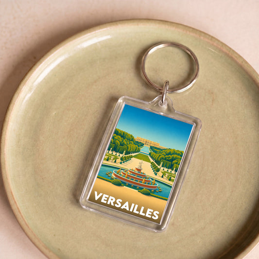 Porte-clés souvenir de la ville de Versailles avec une illustration stylisée de son château et de ses jardins.