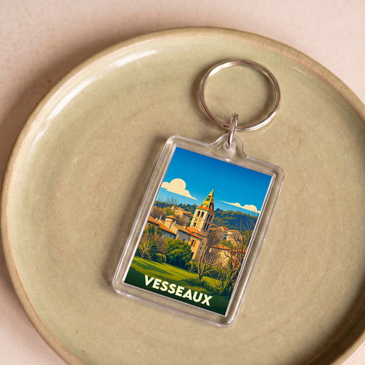 Porte-clés souvenir de la ville de Vesseaux avec une illustration stylisée de son église et de ses paysages.
